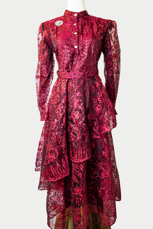 A stunning long layered dress in red with delicate embroidery. The dress has mandarin collar, buttons, long sleeves, and is fully lined. There are hidden zips at the back and sleeves for ease of wear. The design is hijabi-friendly for modesty and style. It also includes a size-adjustable belt for a customized fit.