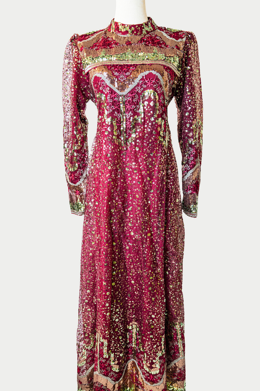 A stunning long dress in red with golden sequins and delicate embroidery. The dress has mandarin collar, long sleeves, and is fully lined. There are hidden zips at the back and sleeves for ease of wear. The design is hijabi-friendly for modesty and style. It also includes a size-adjustable belt for a customized fit.