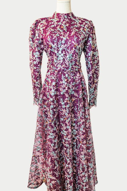 A stunning long dress in purple with sequins and delicate golden embroidery. The dress has mandarin collar, long sleeves, and is fully lined. There are hidden zips at the back and sleeves for ease of wear. The design is hijabi-friendly for modesty and style. It also includes a size-adjustable belt for a customized fit.