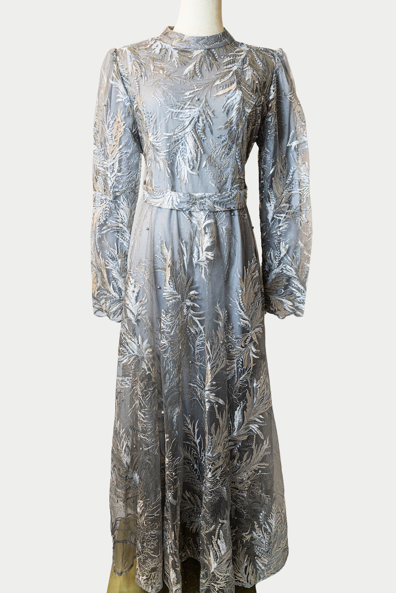 A stunning long dress in grey ombre with pearls and delicate embroidery. The dress has mandarin collar, long sleeves, and is fully lined. There are hidden zips at the back and sleeves for ease of wear. The design is hijabi-friendly for modesty and style. It also includes a size-adjustable belt for a customized fit.